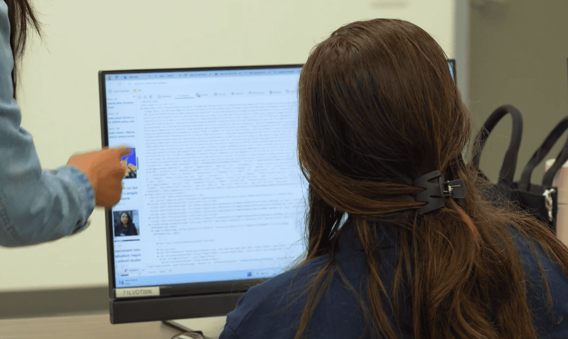 Student and instructor reviewing an AI writing project on a computer